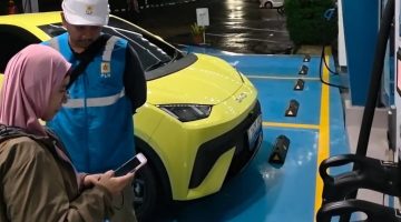 Pengguna EV asal Depok, Jawa Barat, Ufi Desi Fatmawati (kiri) ketika mengisi daya kendaraannya di Rest Area Tol 228A Kanci–Pejagan pada Rabu (24/12). Menurutnya, ketersediaan fasilitas pengisian daya di sepanjang jalur mudik memberikan rasa tenang selama perjalanan menuju kampung halamannya di Purwokerto, Jawa Tengah.